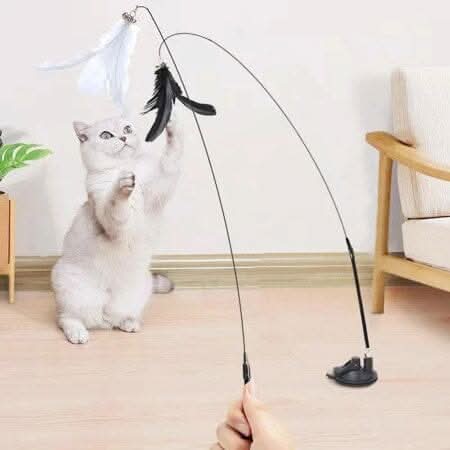 Brinquedo interativo para gatos com pena, sino e ventosa em ambiente de sala, promovendo diversão