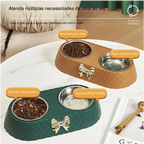 Cachorro feliz próximo à tigela dupla para pets com acabamento matelassê e detalhe em laço dourado